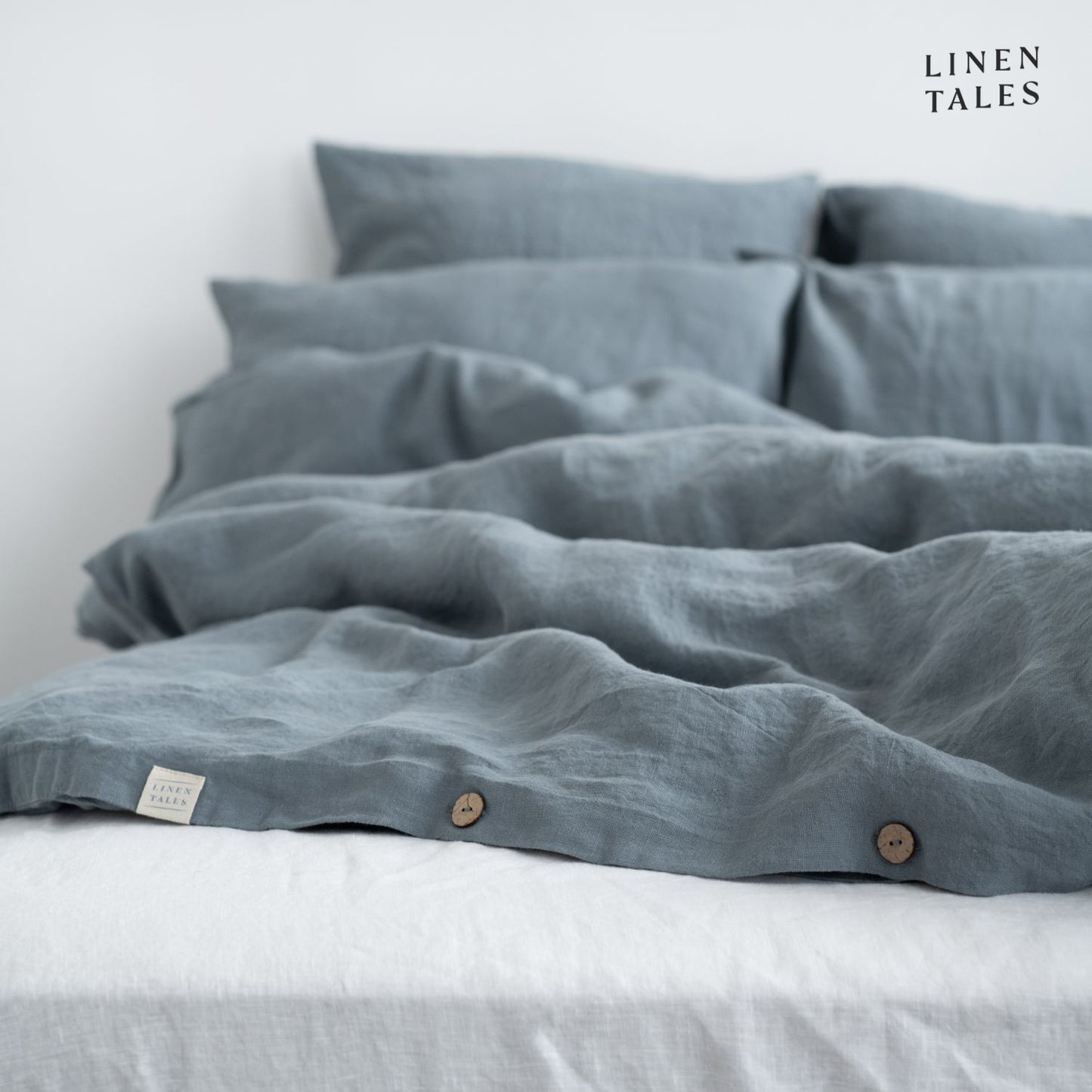 Close-up of Blue Fog linen duvet cover opening, featuring natural wooden buttons for a refined and functional finish.