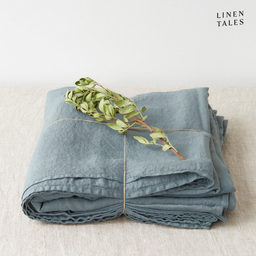 A folded fitted 100% pure linen flat sheet in a serene blue fog hue, evoking a misty coastal morning.