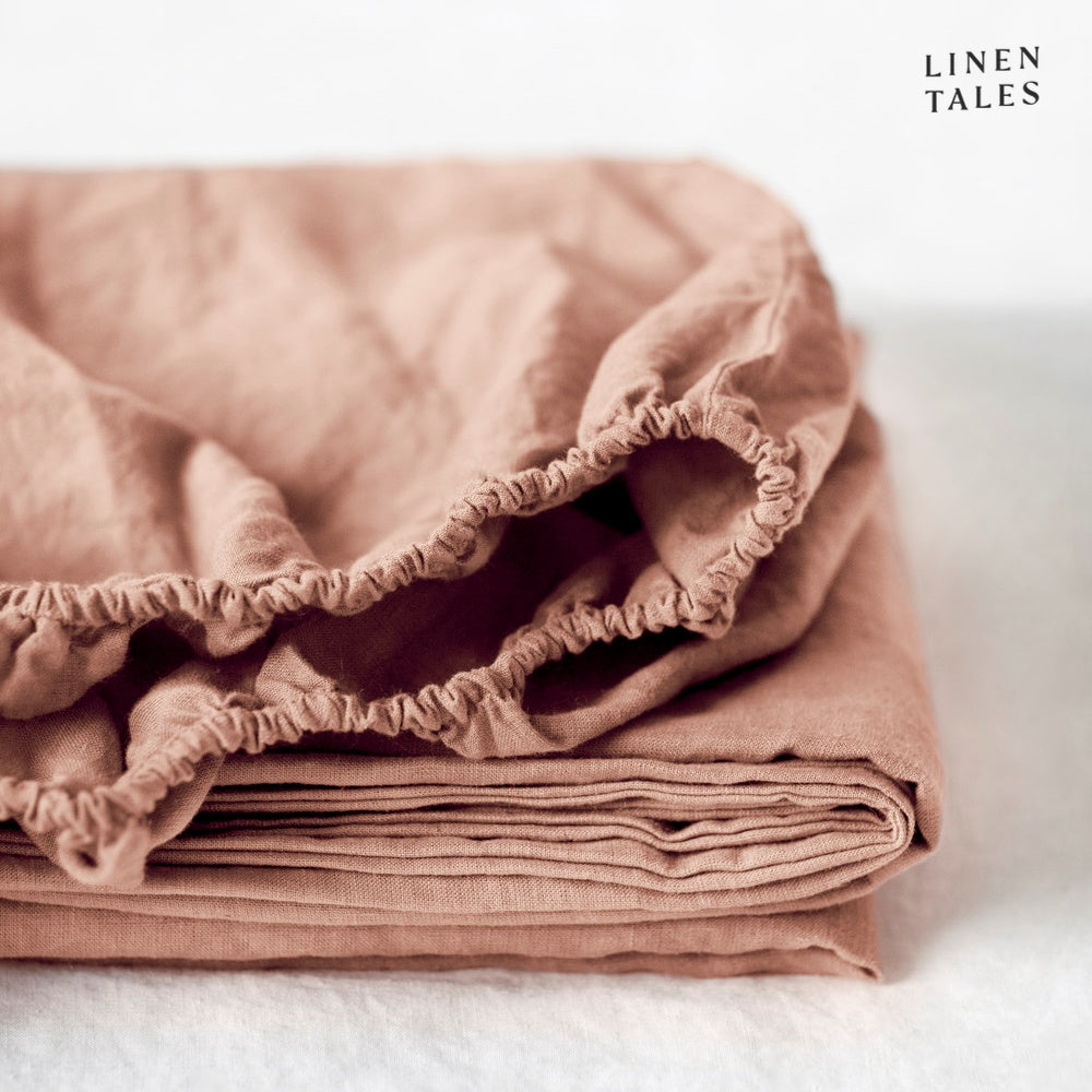 A warm beige fitted sheet, neatly folded, made from sustainable certified 100% pure linen moisture-wicking, breathable, and effortlessly refined.