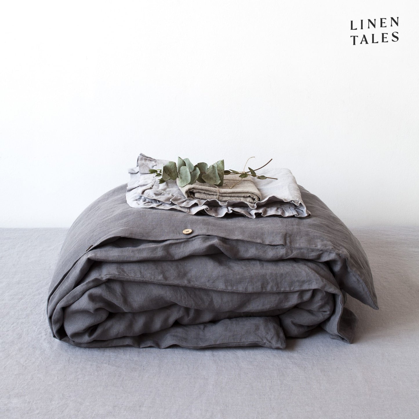A folded 100% pure linen duvet cover in deep dark grey, exuding understated sophistication and a relaxed feel.