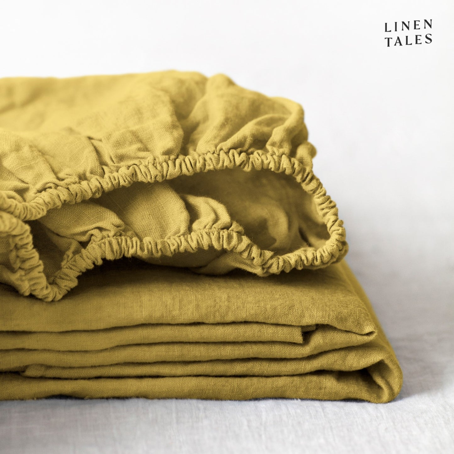 A bold golden linen fitted sheet, ethically made with certified 100% pure linen folded to showcase its breathable, eco-conscious softness.
