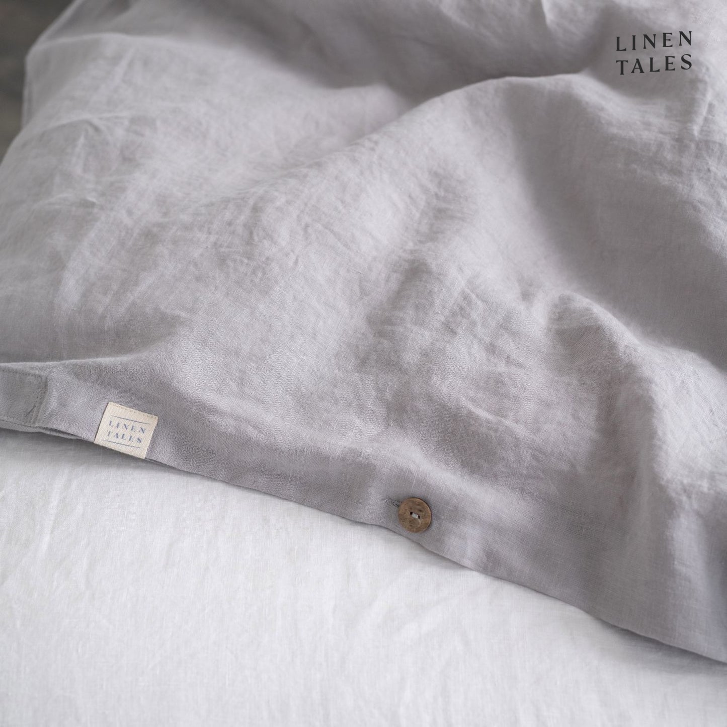 Fine edge stitching and branded Linen Tales tag on Light Grey linen duvet cover, showcasing craftsmanship and premium quality.