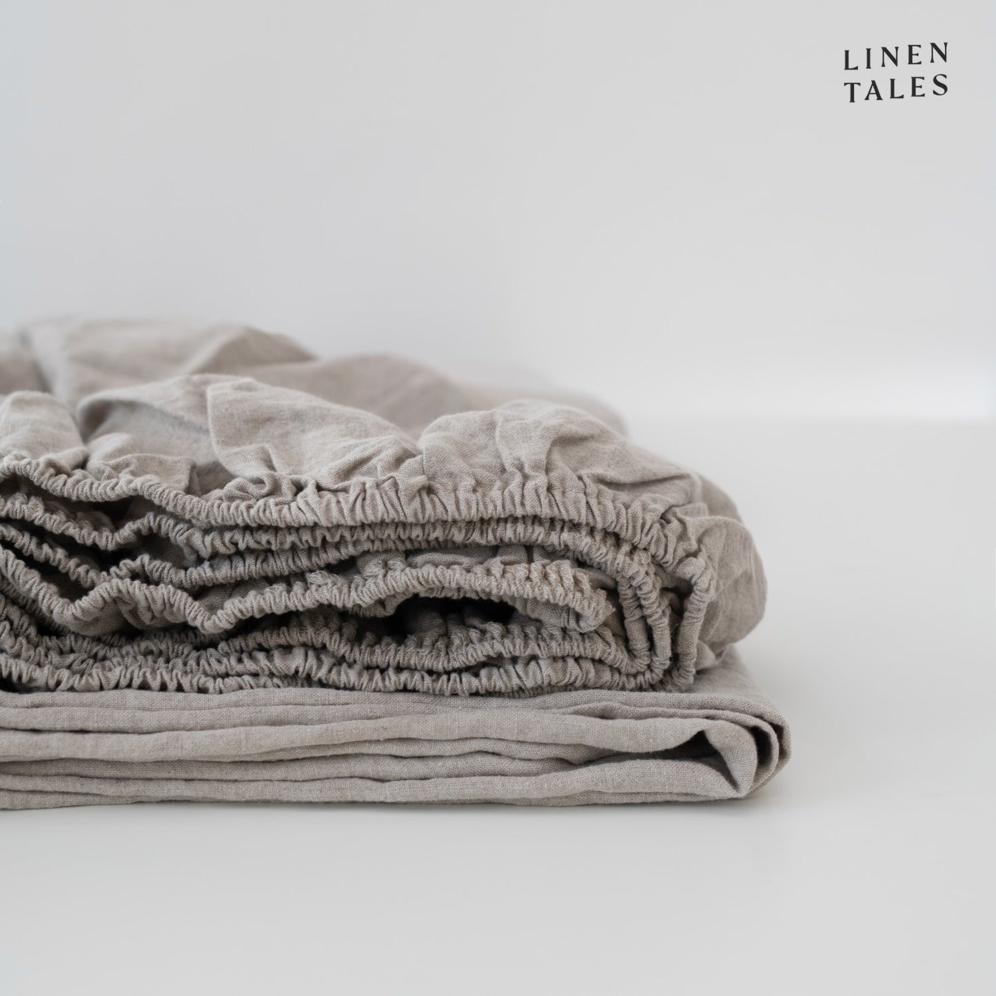 A folded natural linen fitted sheet, undyed and organic, made from certified 100% pure European linen timeless sustainability and effortless softness
