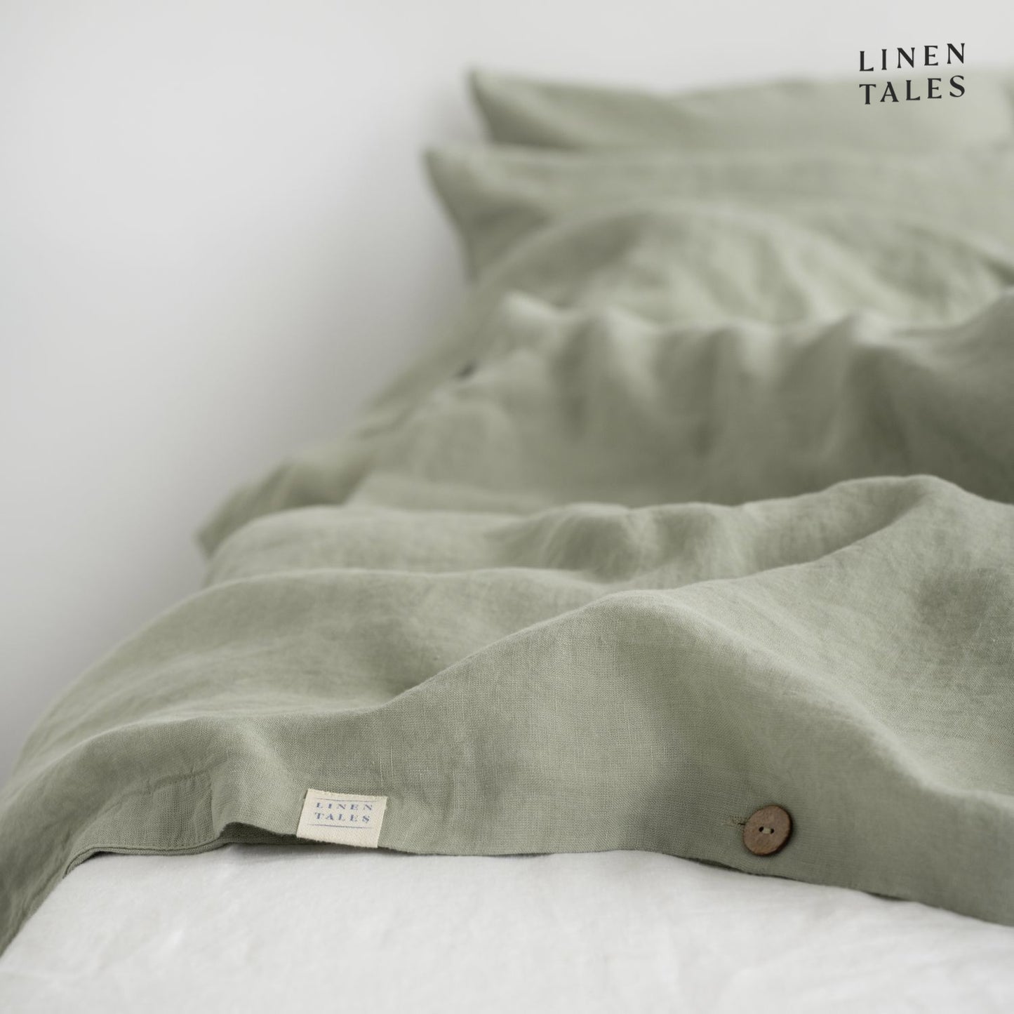 Fine edge stitching and branded Linen Bay tag on Sage linen duvet cover, showcasing craftsmanship and premium quality.