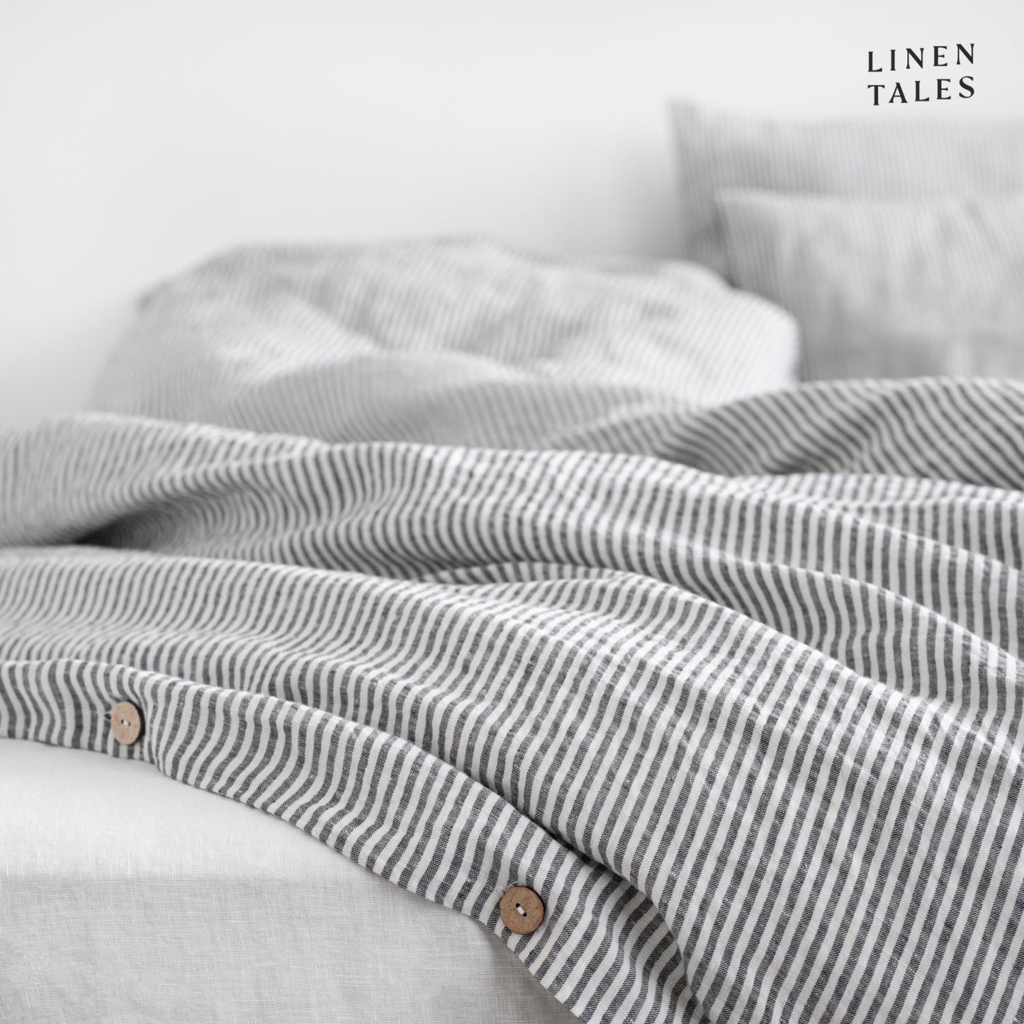 Layered look of thin black striped linen duvet set with coordinating sheet, offering effortless comfort and timeless style.