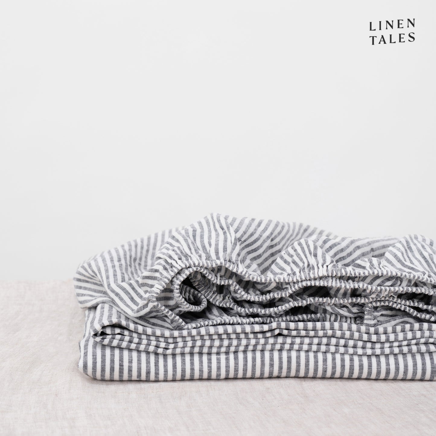 A sleek striped linen fitted sheet, crafted from certified 100% pure linen folded to highlight its modern, breathable, and sustainable design.
