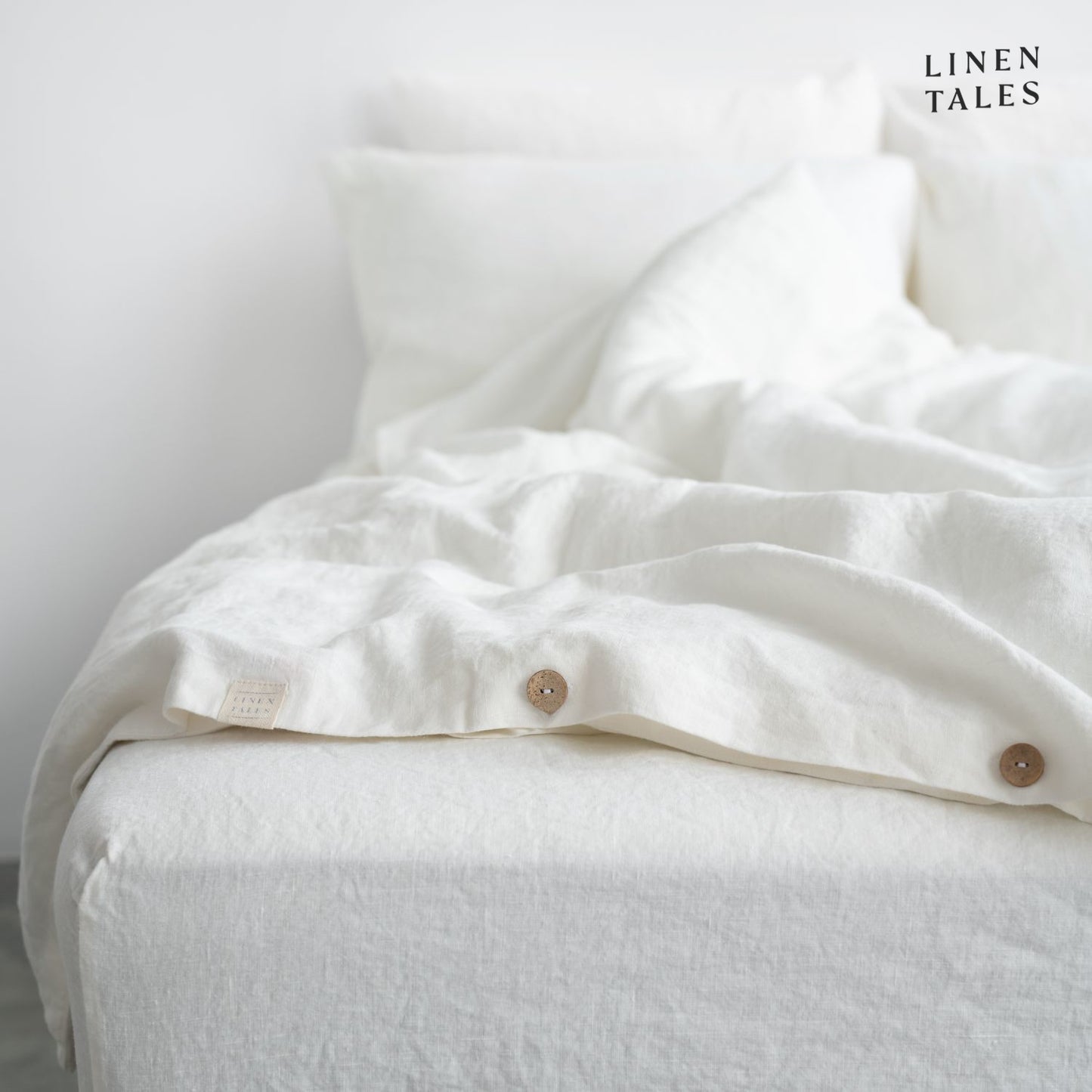 Close-up of White linen duvet cover opening, featuring natural wooden buttons for a refined and functional finish