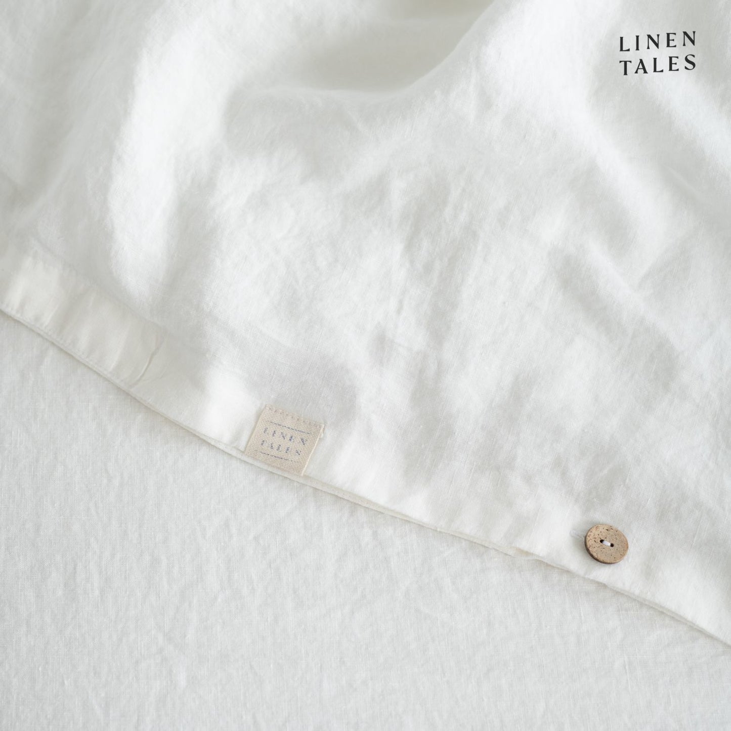 Fine edge stitching and branded Linen Tales tag on White linen duvet cover, showcasing craftsmanship and premium quality.