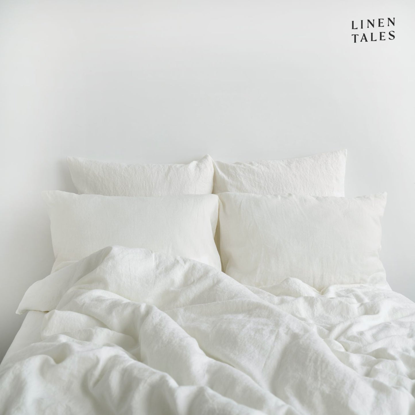 Beautifully made bed featuring White linen duvet set and pillows, styled for luxurious comfort and breathable relaxation.