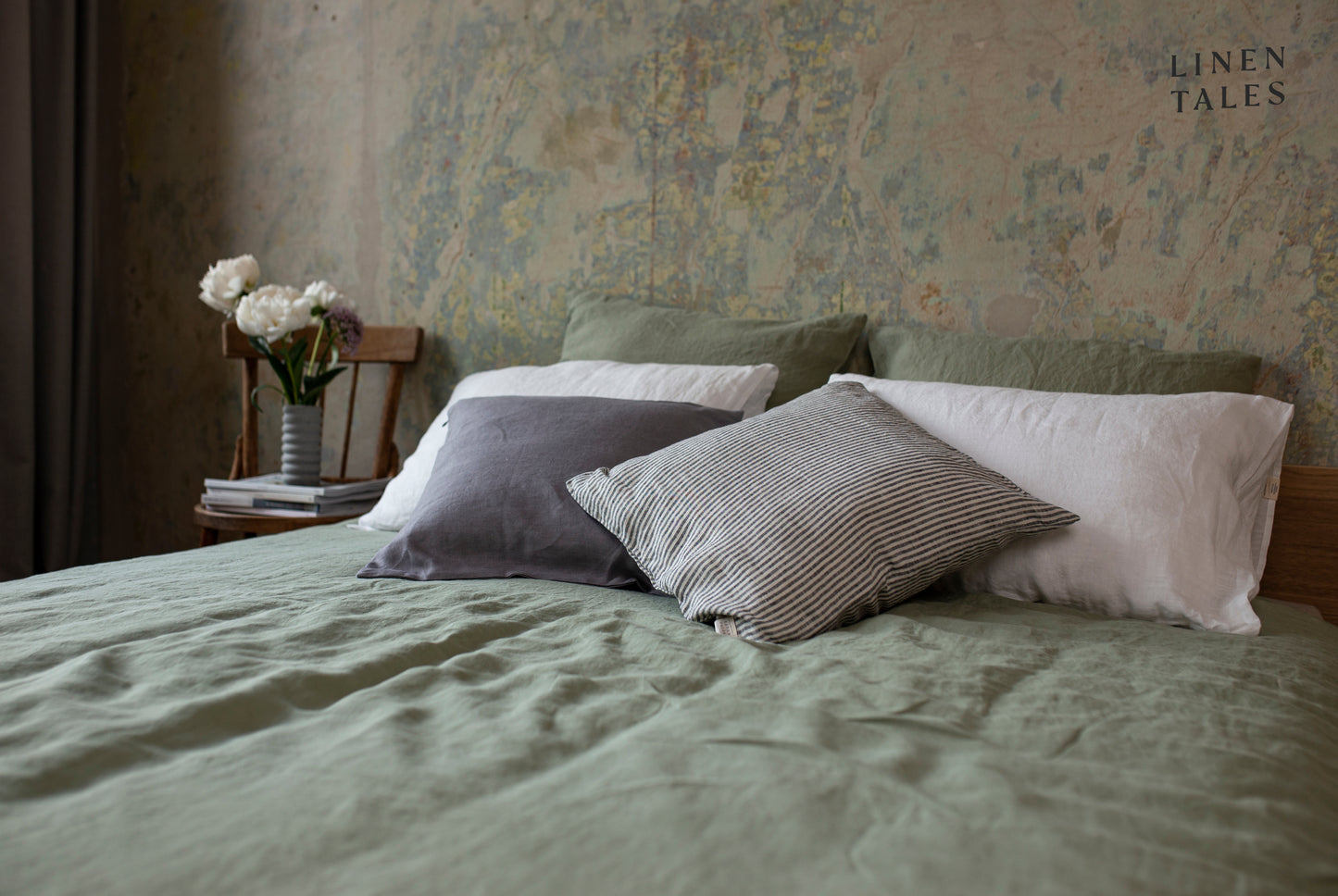 A neatly made bed featuring a sage-colored linen duvet cover set, draped softly for a fresh, calming, and elegant look.