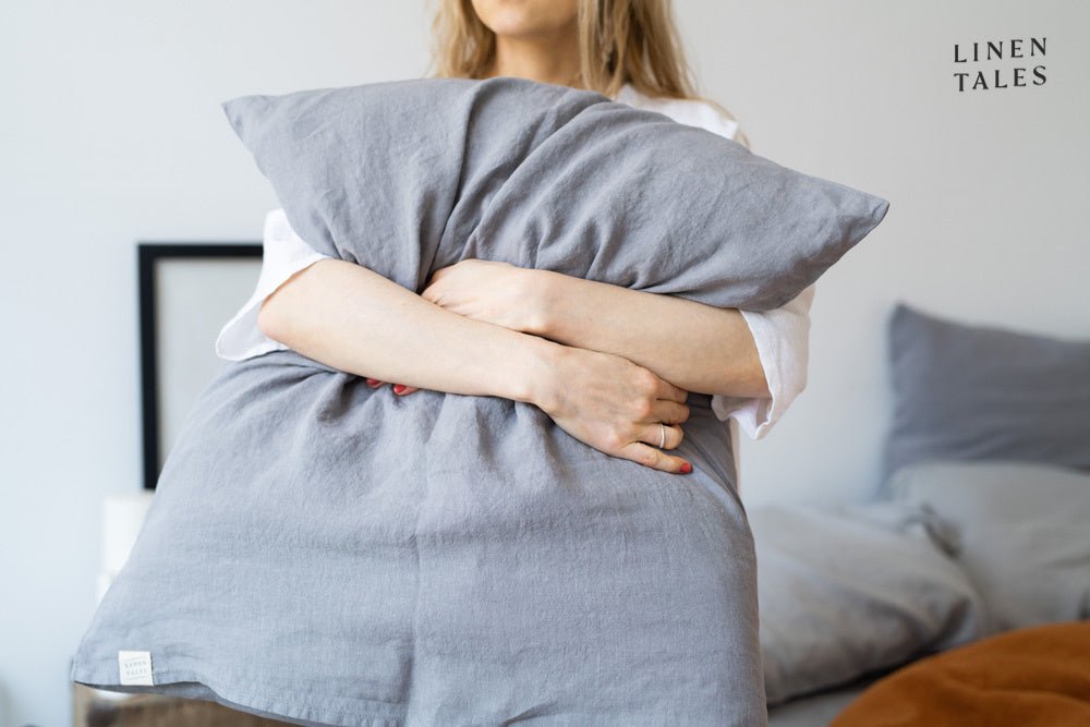 Woman embracing a soft blue linen pillow from Linen Bay crafted from 100% flax linen for breathable comfort and serene sleep styling