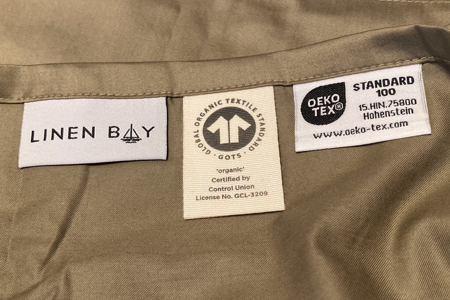 Close-up of Linen Bay bedding with GOTS and OEKO-TEX® Standard 100 labels, showcasing ethical sourcing and certified sustainability