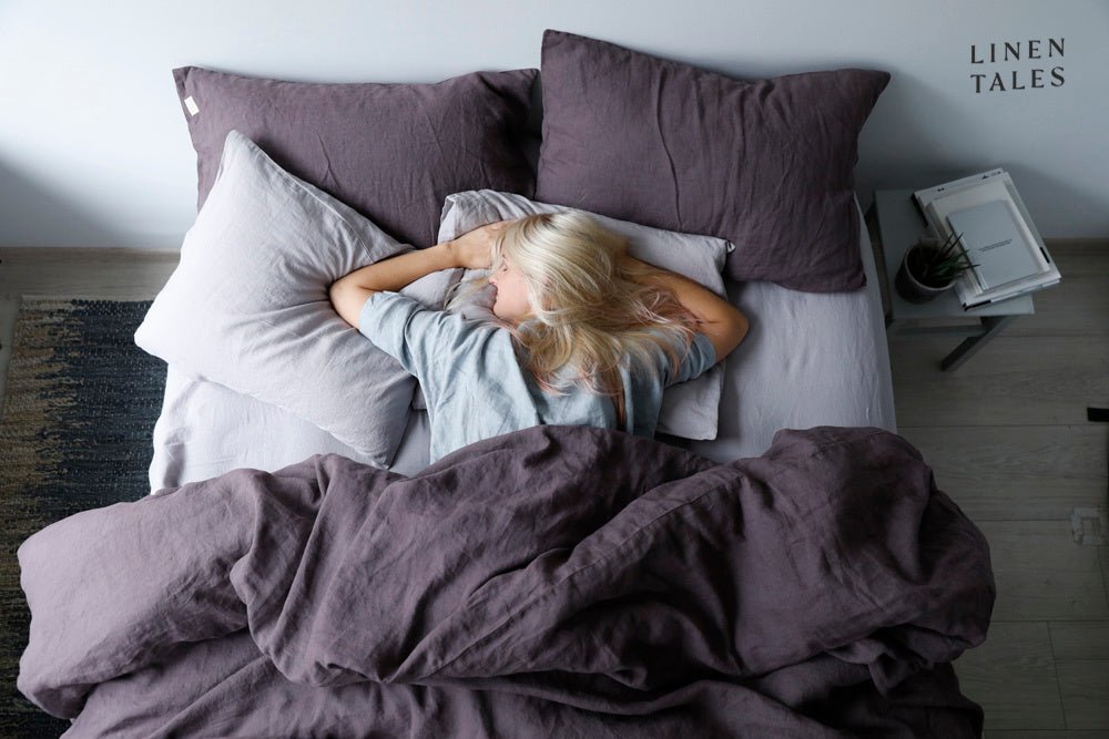 Blonde-haired woman peacefully asleep on Linen Bay pillows, wrapped in a soft flax linen duvet natural comfort and serene sleep styling