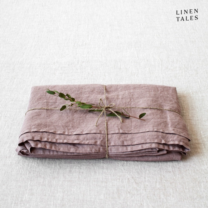 A folded fitted 100% pure linen flat sheet in romantic ashes of roses, a muted blush with understated charm.