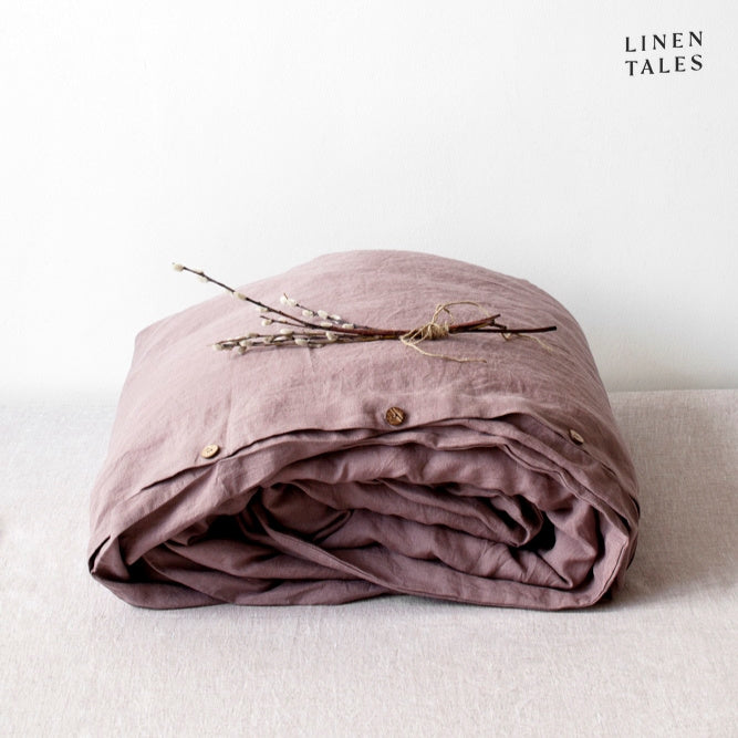 A folded 100% pure linen duvet cover in delicate ashes of roses, a muted blush with refined charm.