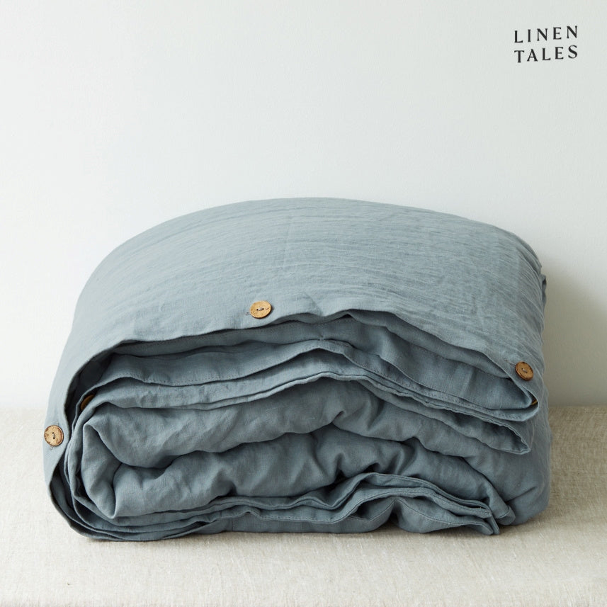 A folded 100% pure linen duvet cover in misty blue fog, evoking a fresh coastal morning.
