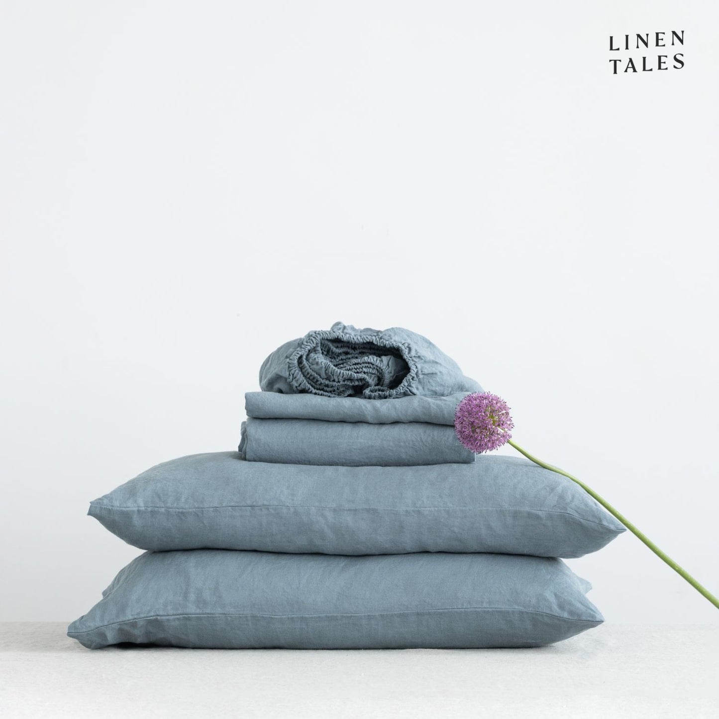 Close-up of 100% linen bedding in Blue Fog, showcasing the soft texture of the flat sheet, fitted sheet, and pillowcase – breathable and timeless.