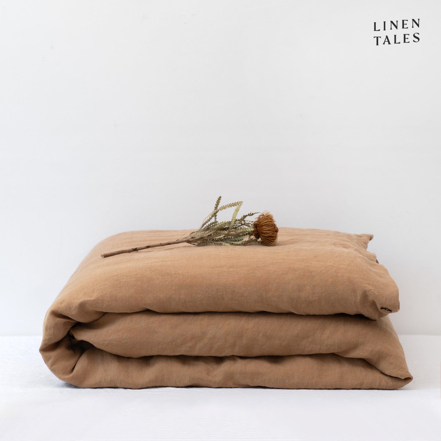 A folded 100% pure linen duvet cover in warm camel, showcasing its rich, earthy hue and natural elegance.