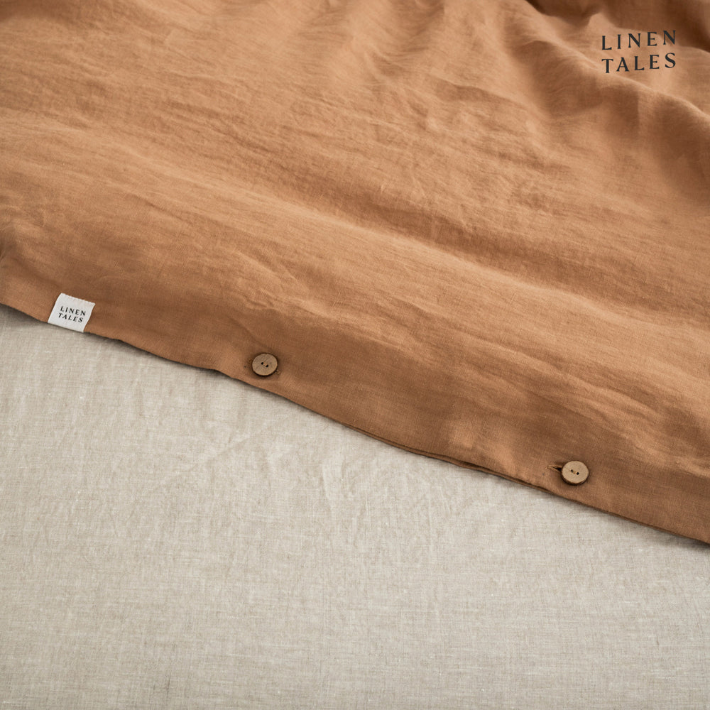 
                  
                    Close-up of Camel linen duvet cover opening, featuring natural wooden buttons for a refined and functional finish.
                  
                