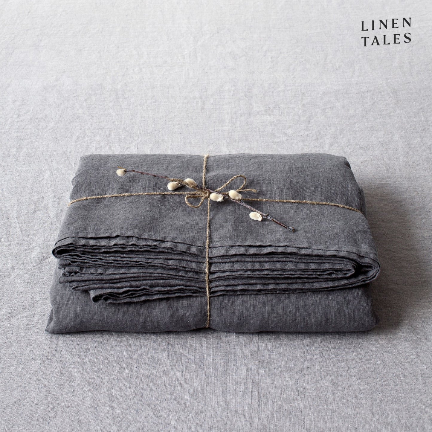 A folded fitted 100% pure linen flat sheet in deep, sophisticated dark grey, highlighting its smooth, relaxed drape.