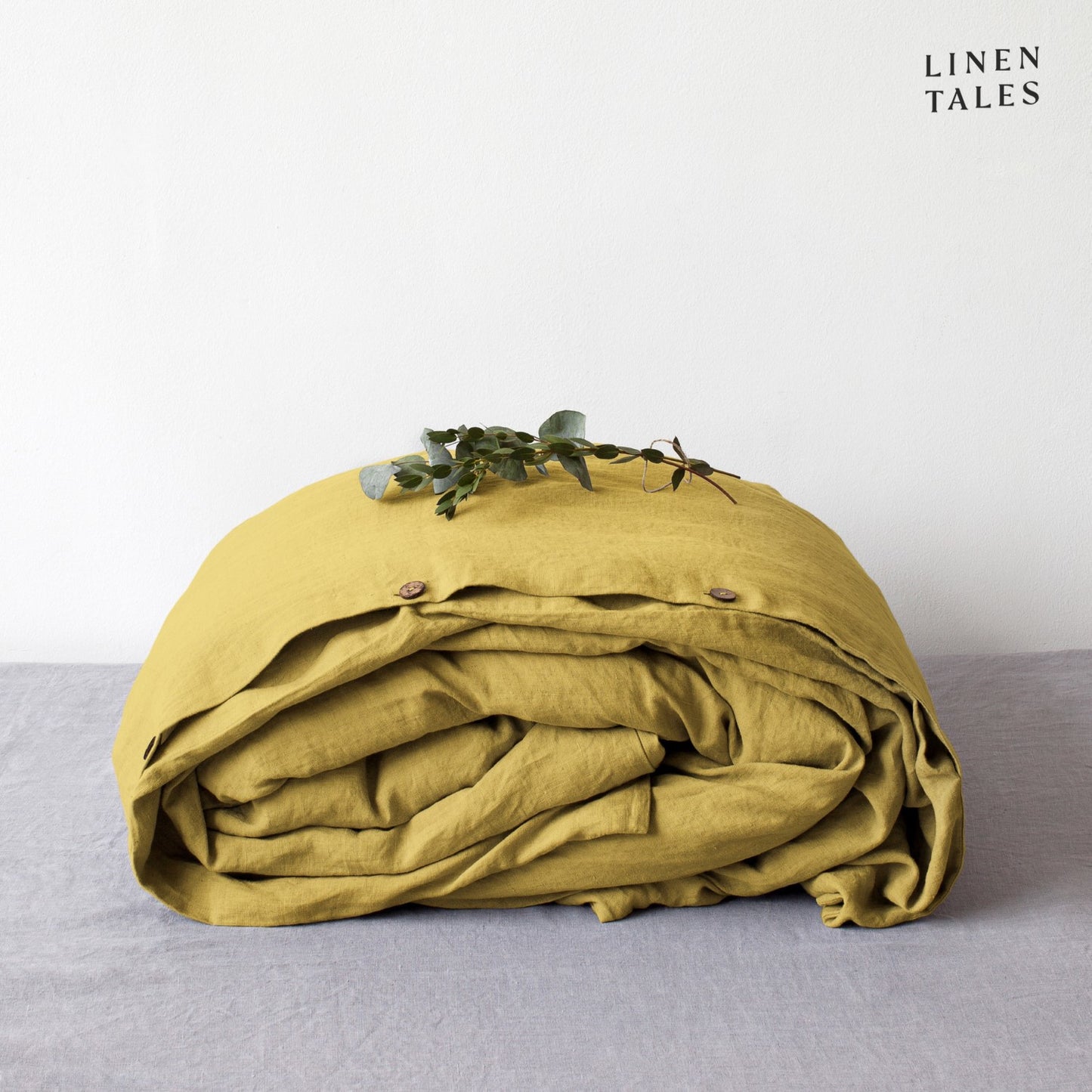 A folded 100% pure linen duvet cover in bold lemon curry, adding a vibrant golden glow to any space.