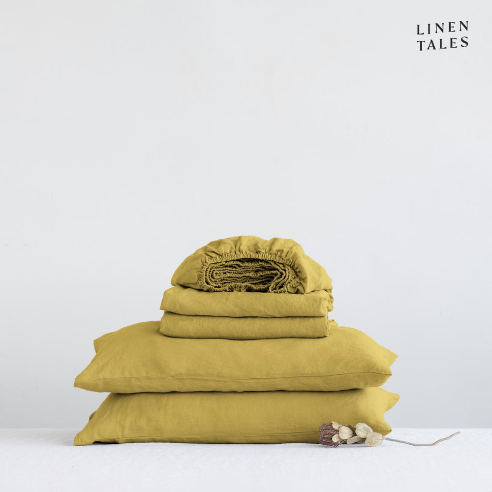 Close-up of 100% linen bedding in Lemon Curry, showcasing the soft texture of the flat sheet, fitted sheet, and pillowcase – breathable and timeless.