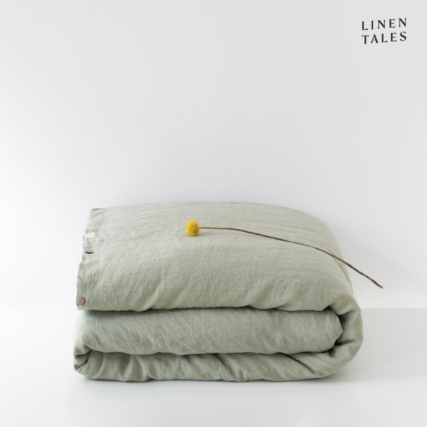 A folded 100% pure linen duvet cover in soft sage green, bringing a calming, botanical-inspired touch to bedding.