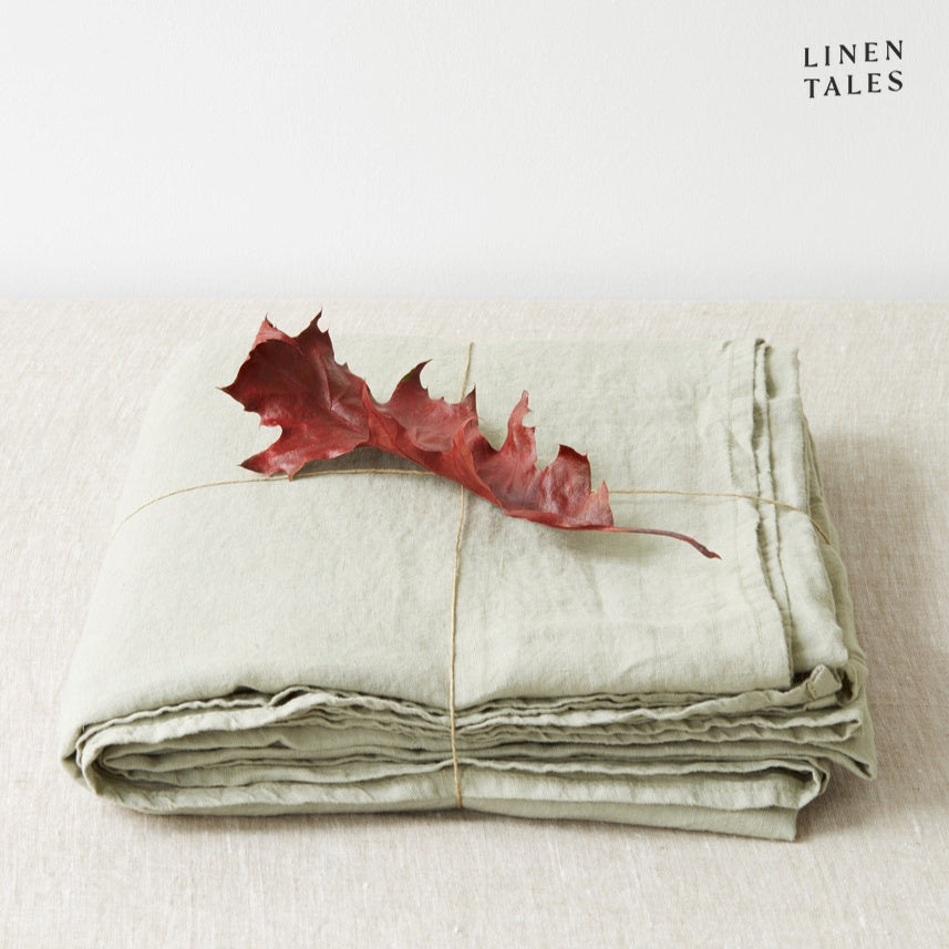 A folded fitted 100% pure linen flat sheet in soft sage green, offering a fresh and tranquil feel.