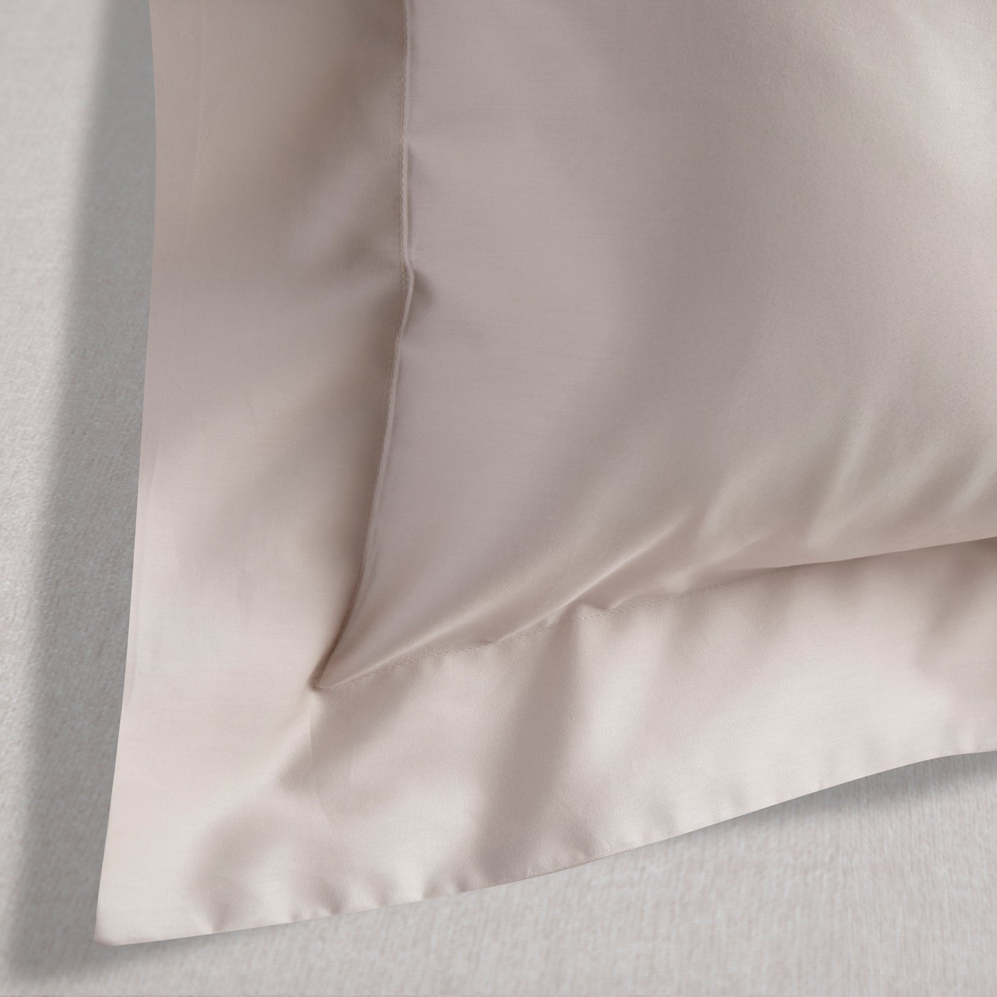Close-up of a light driftwood natural organic cotton pillowcase on a matching fabric background