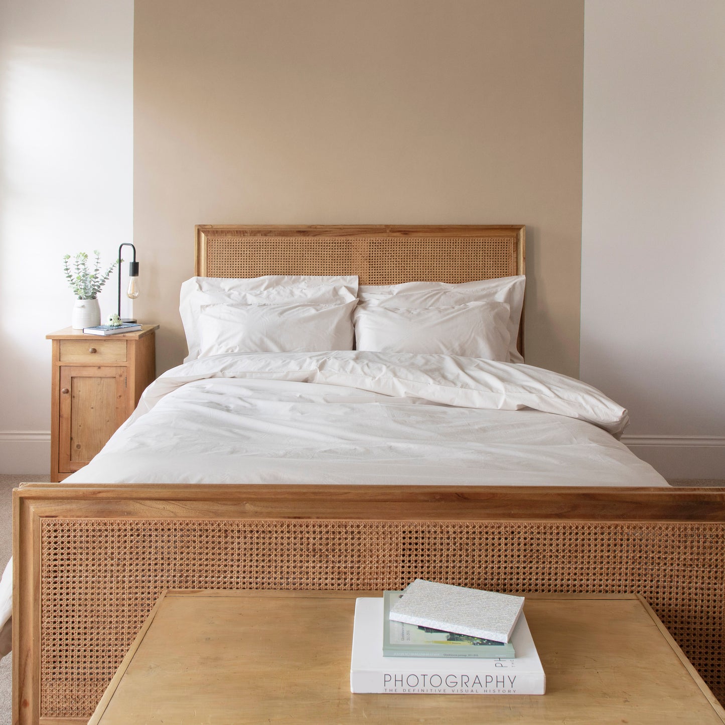 Bedroom with wooden bed frame and driftwood, neutral 100% Organic Cotton bedding, with duvet set including duvet cover, pillowcases and fitted sheets.