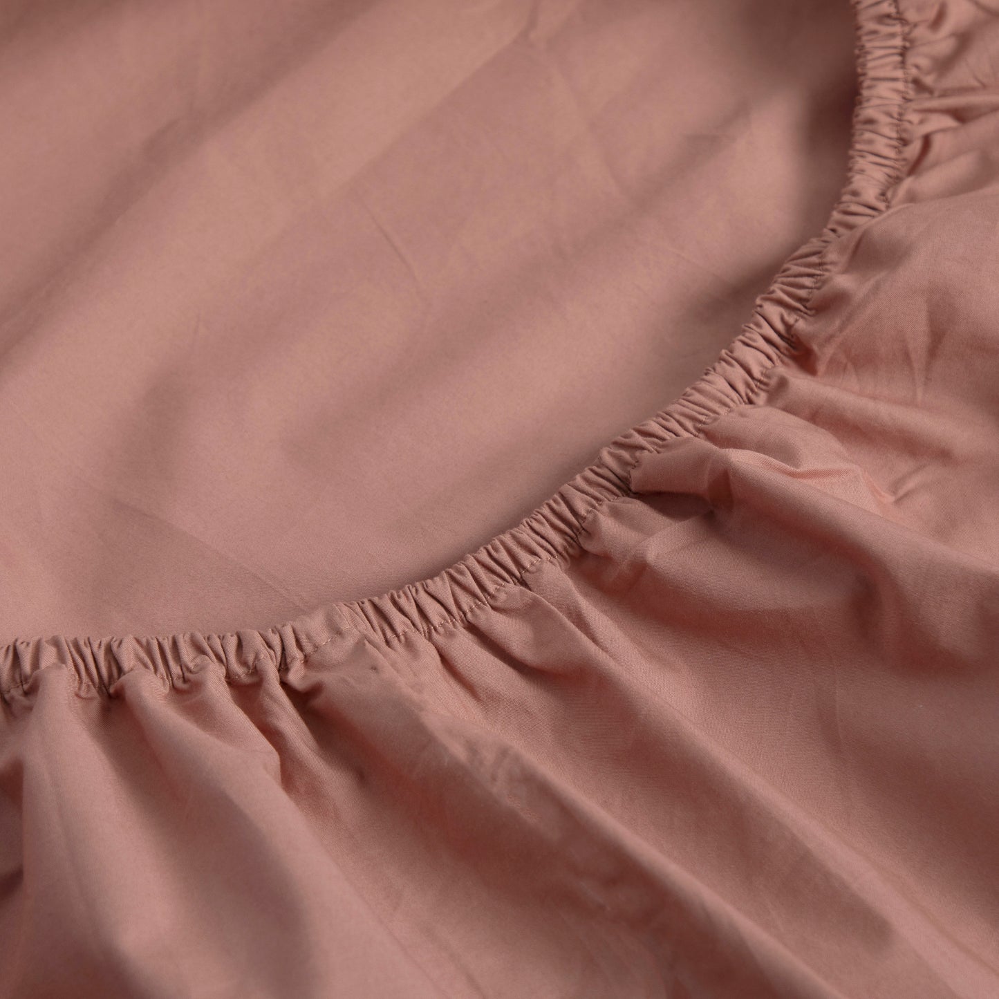 Close-up of a dune shadow 100% pure cotton Linen Bay fitted sheet with a elasticized edge on a bed.