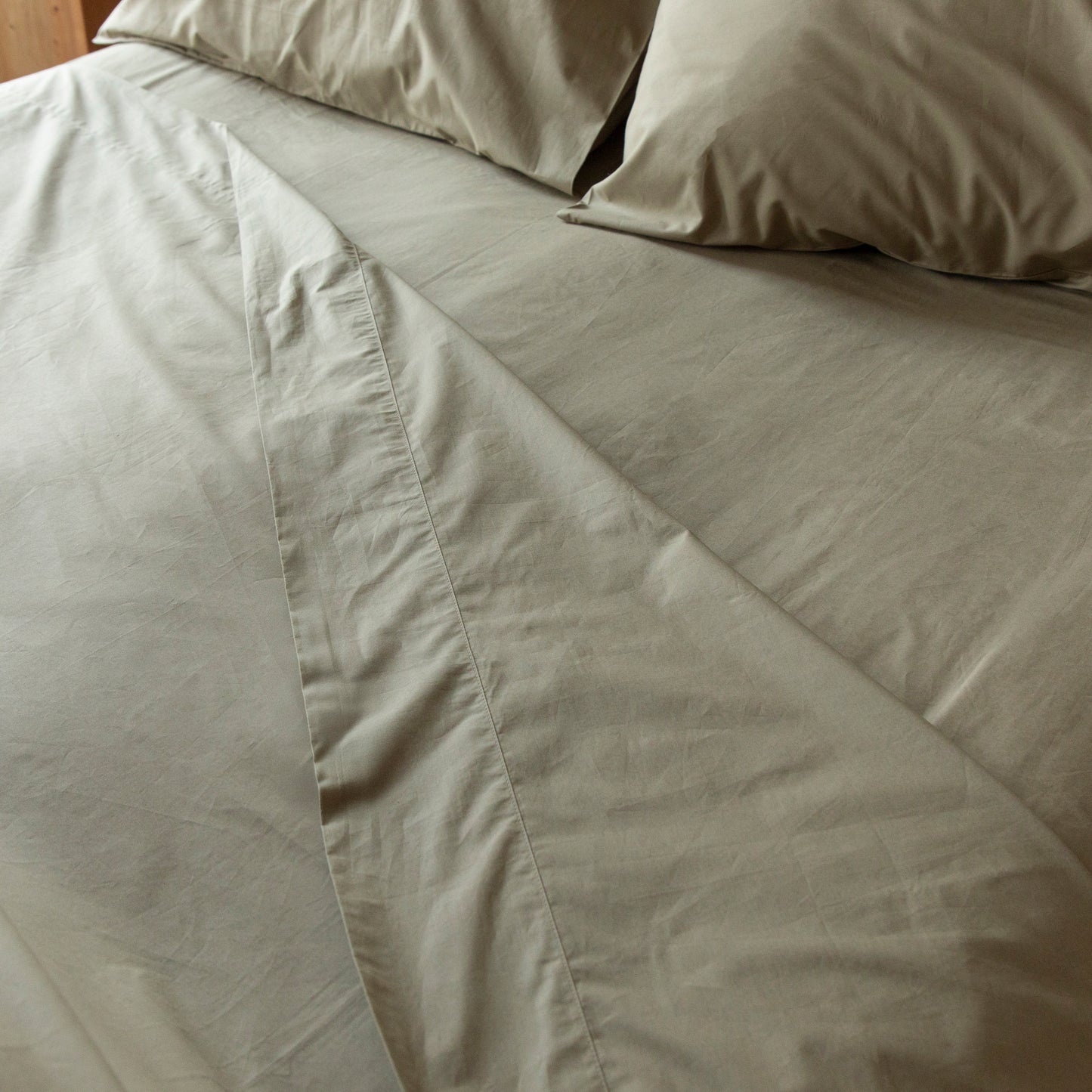 Close-up of sea fern dark green flat sheet bedding manufactured from 100% pure cotton GOTS certified with a matching pillow on a bed