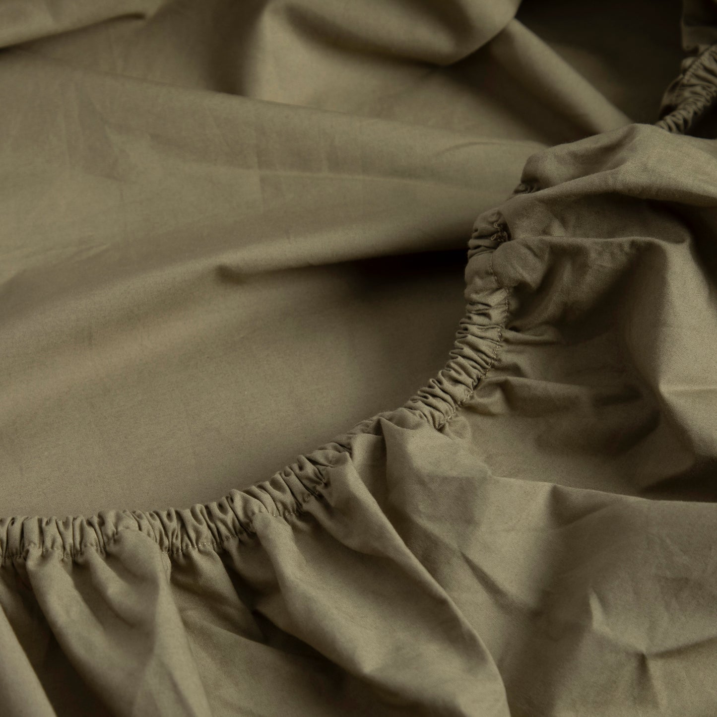 Close-up of a 100% pure cotton GOTS certified sea fern green fitted sheet with elastic waistband