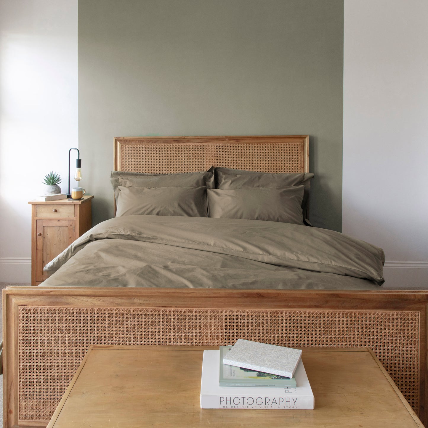 Bedroom with wooden bed frame, nightstand, and books on a table. Seafern 100% pure organic cotton duvet cover set with pillowcases and fitted sheets.