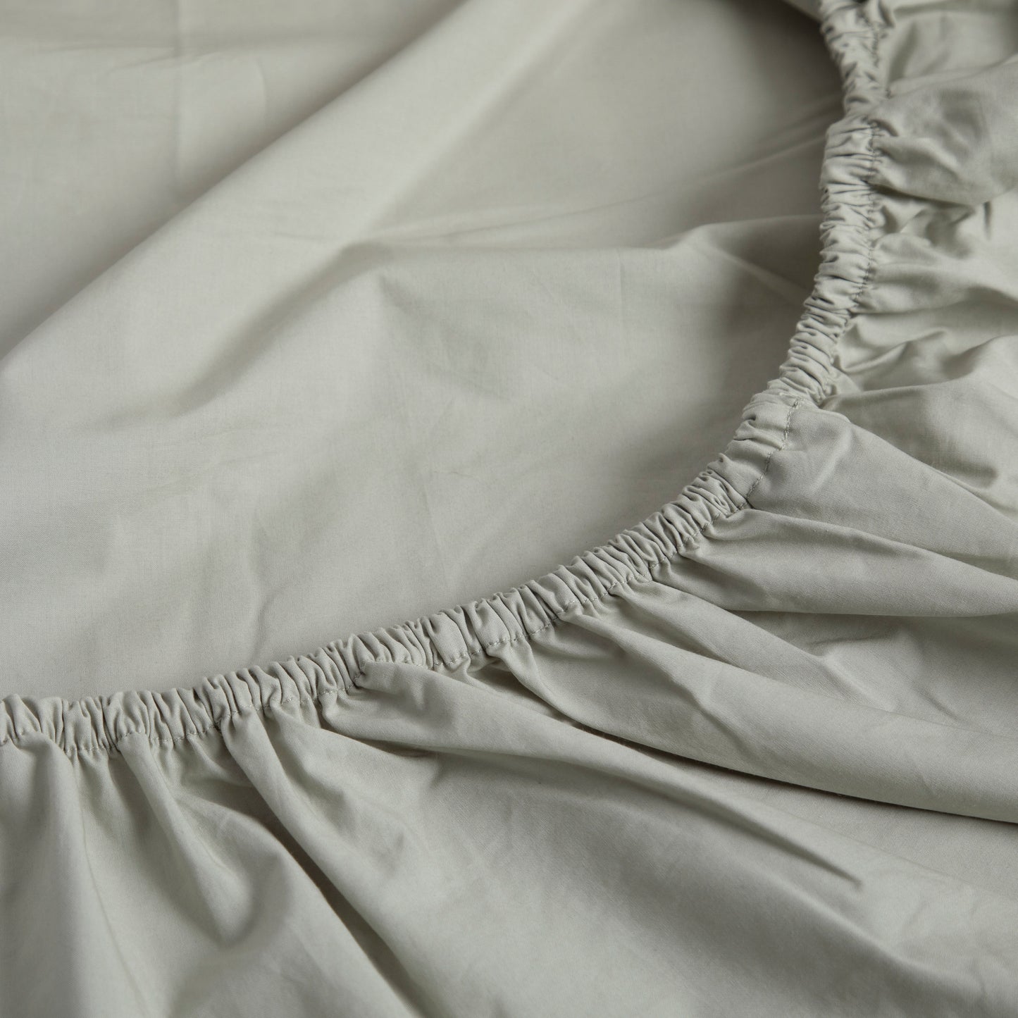 Close-up of a seagrass green 100% pure cotton GOTS certified fitted sheet.