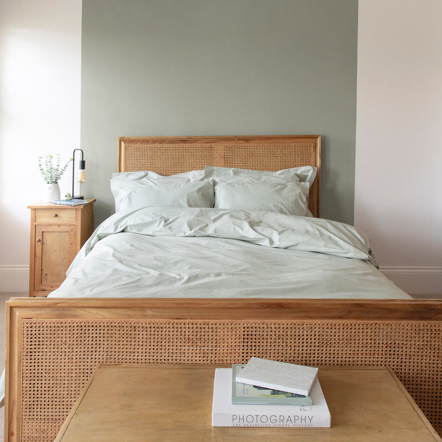 Wooden bed with 100% organic cotton bedding including duvet cover,  bedsheets and pillow cases, in Seagrass green in a bedroom setting