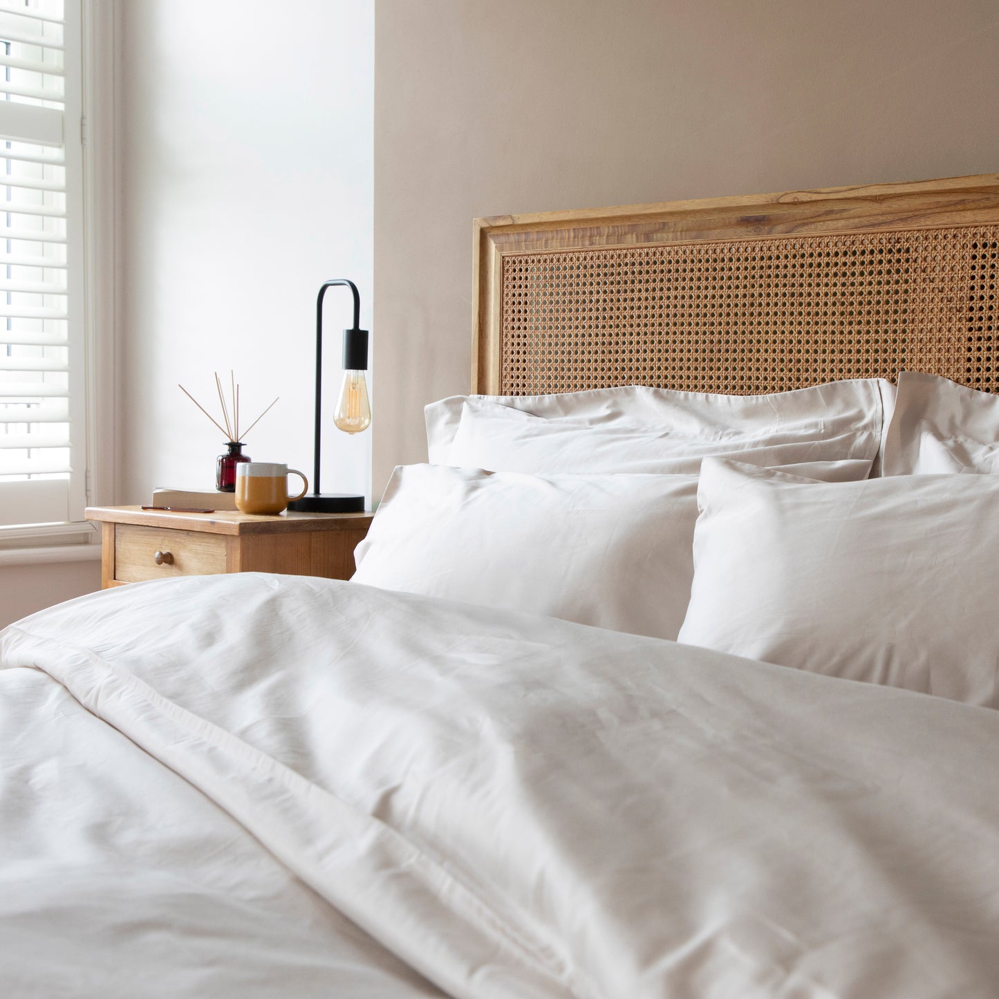 Neatly made bed with driftwood natural cotton bedding and pillows in a bedroom setting – Linen Bay UK