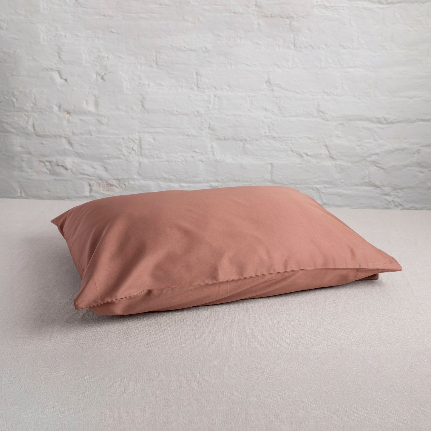 Dune Shadow coloured pillow on a neutral fabric with a light gray wall background – Linen Bay UK