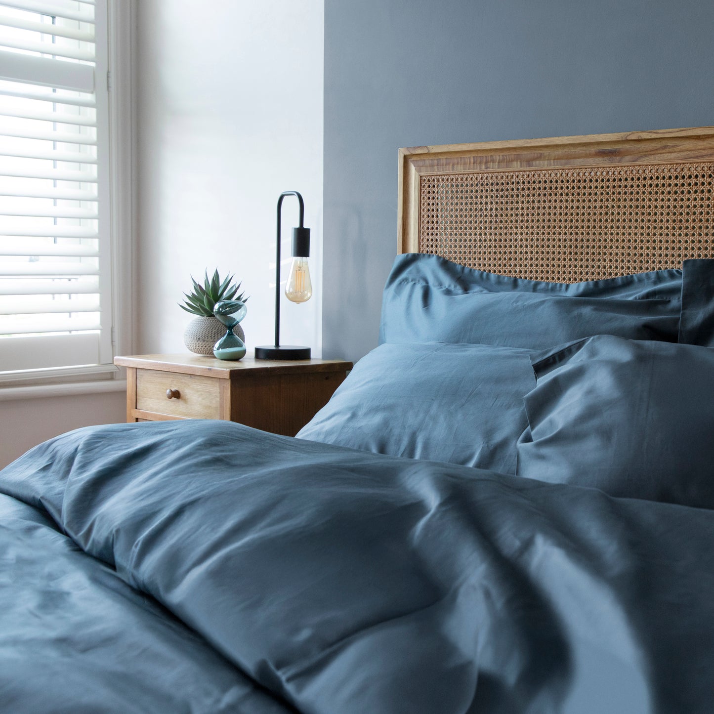 Bed with sargasso blue bedding and a wooden headboard in a bedroom setting – Linen Bay UK