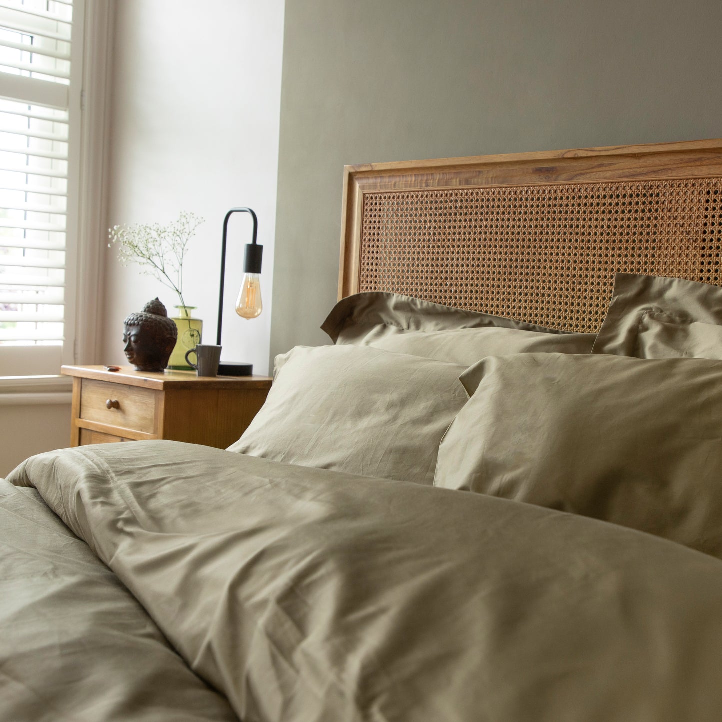 Bedroom with a wooden headboard and seafern green 100%pure bedding