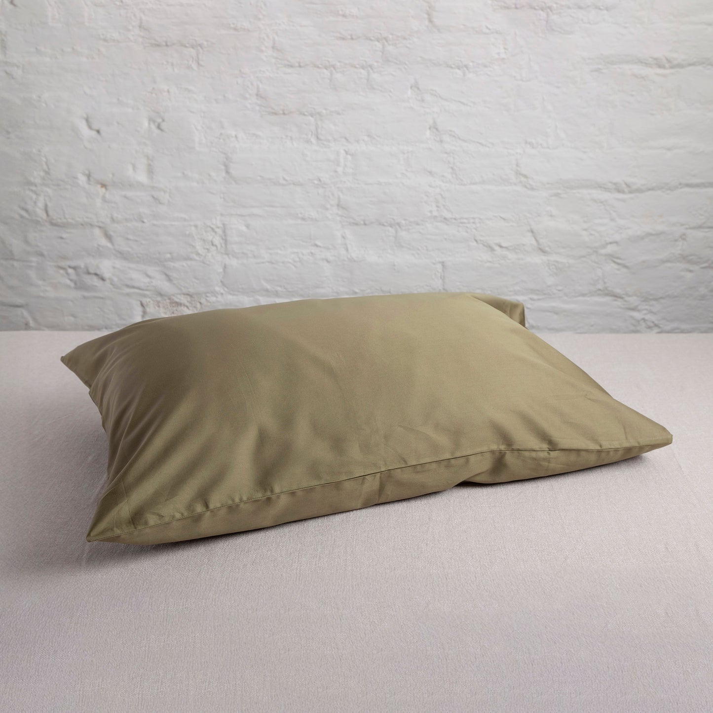 seag fern coloured green pillow on a bed with a light gray wall background – Linen Bay UK