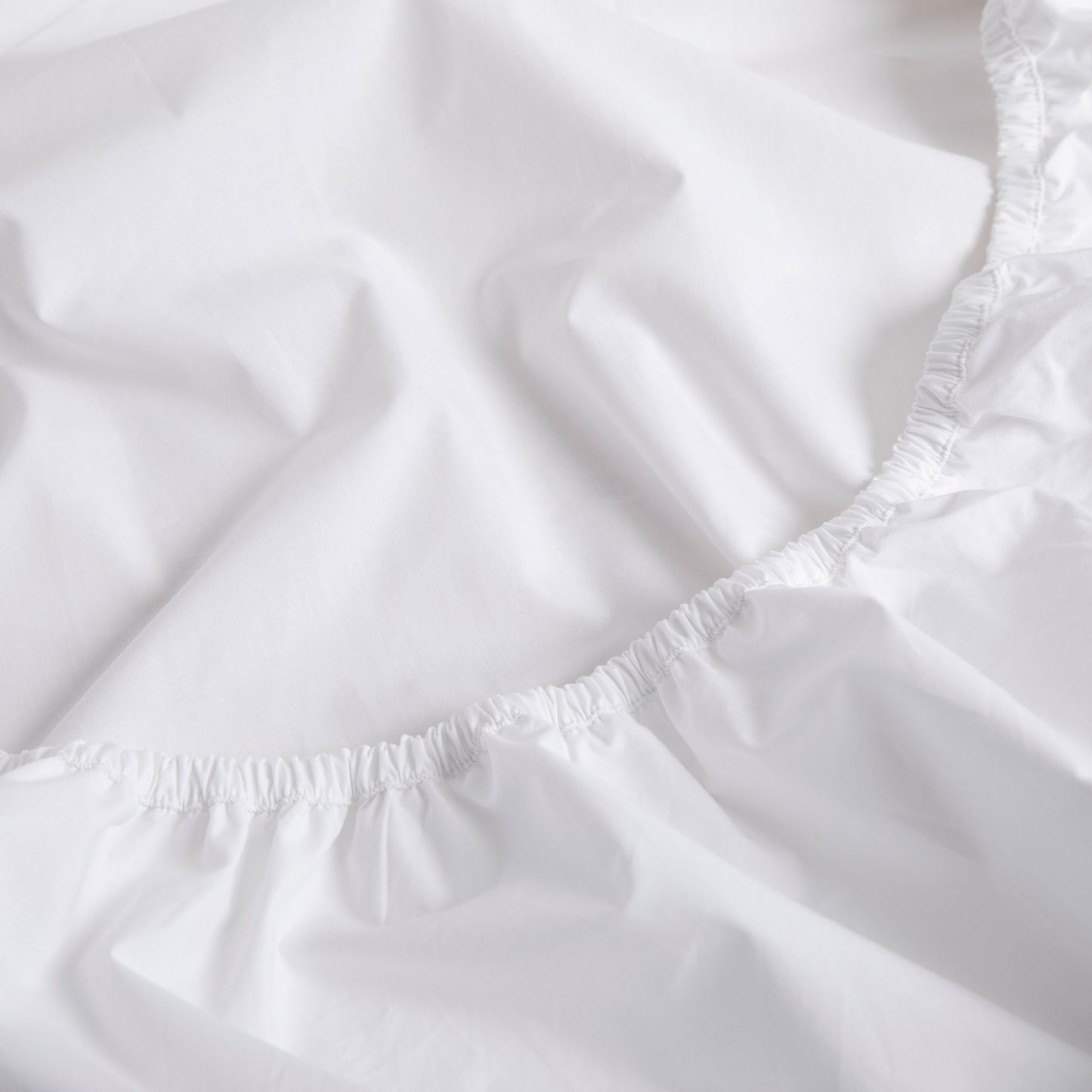 Close-up of a white fitted sheet with elastic waistband