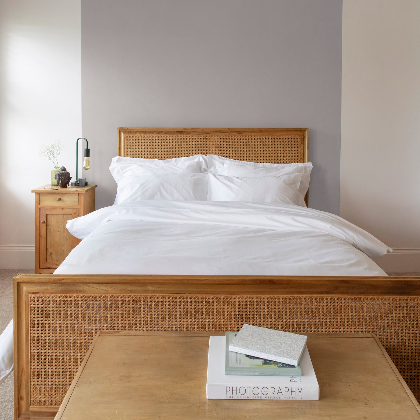 Bedroom with wooden bed frame, sea salt white 100% certified pure organic bedding, and a small table with book
