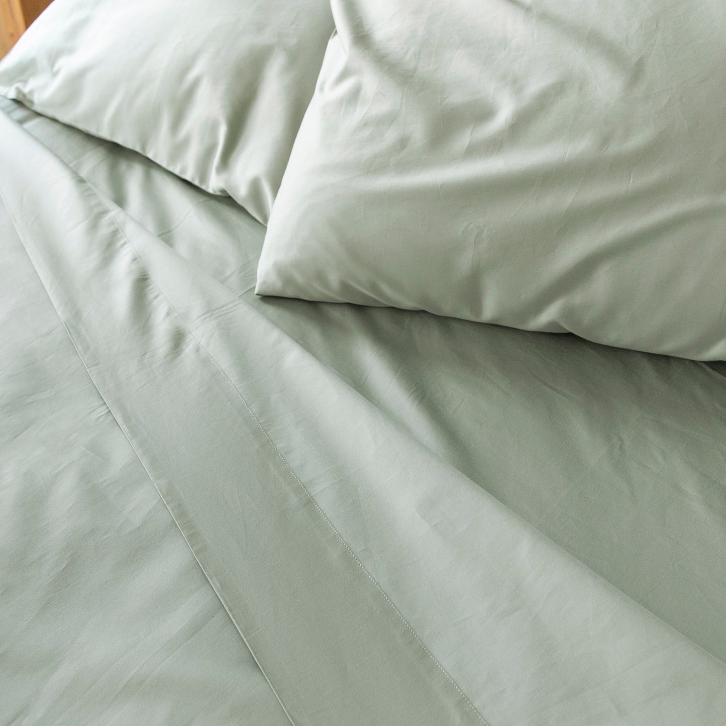 Close-up of seagrass green bedding with pillows on a bed – Linen Bay UK