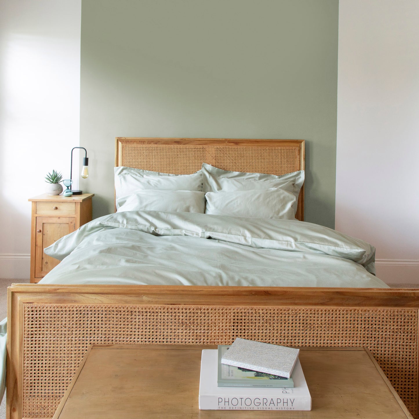 Sea Grass Green duvet and pillowcases on a bed in a bedroom with wooden bed frame and nightstand, featuring a calm and neutral color palette – Linen Bay UK