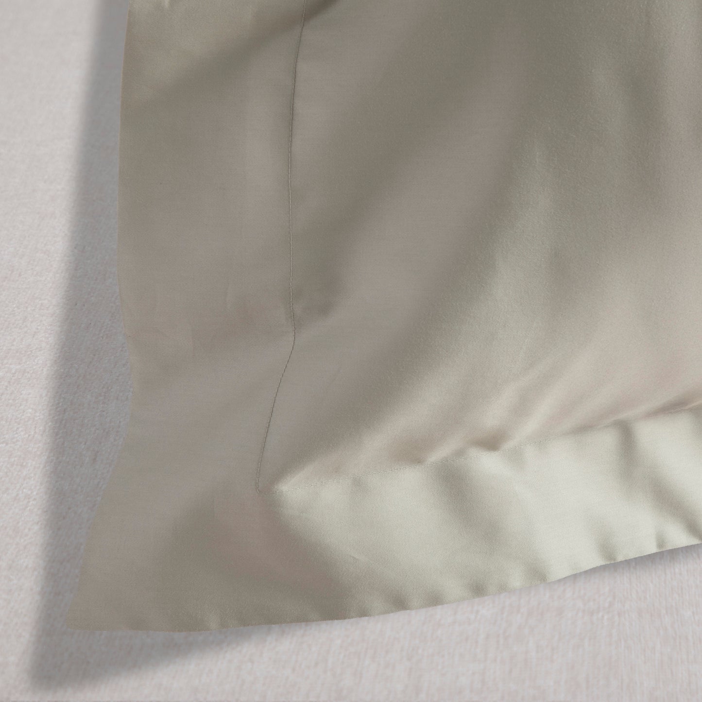 Close-up of Oxford pillow case corner in Seagrass Green fabric with a subtle texture on a white background 