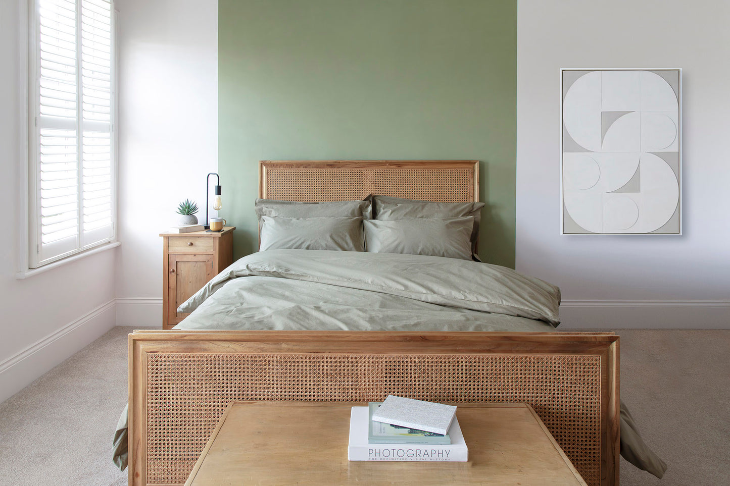Bedroom with wooden bed frame, green bedding, and a nightstand.