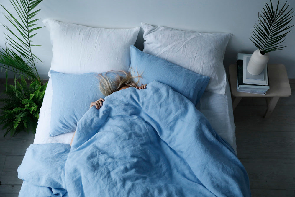 A neatly made bed featuring a deep blue linen duvet cover set, paired with crisp white pillowcases, creating a stylish contrast and a serene, inviting atmosphere.