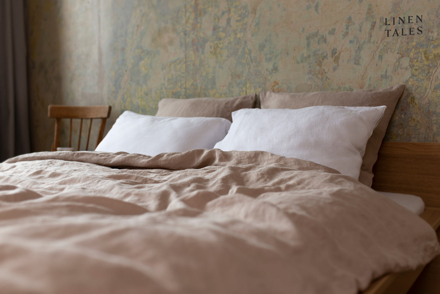 A neatly made bed featuring a warm sand-colored linen duvet cover set, draping softly over the mattress, creating a cozy and inviting atmosphere.